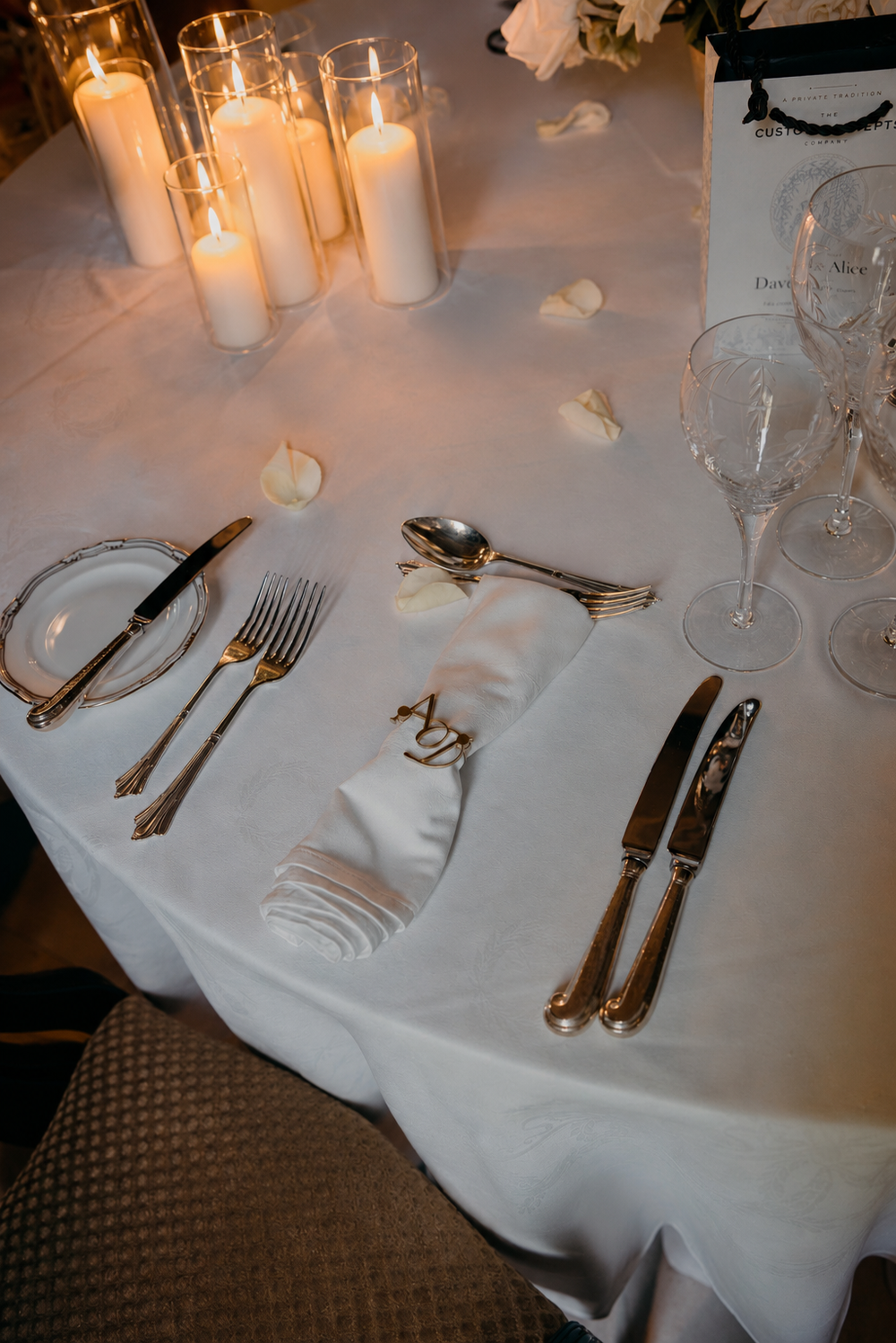 Gold entwined monogram napkin ring on a candlelit table at a private dinner