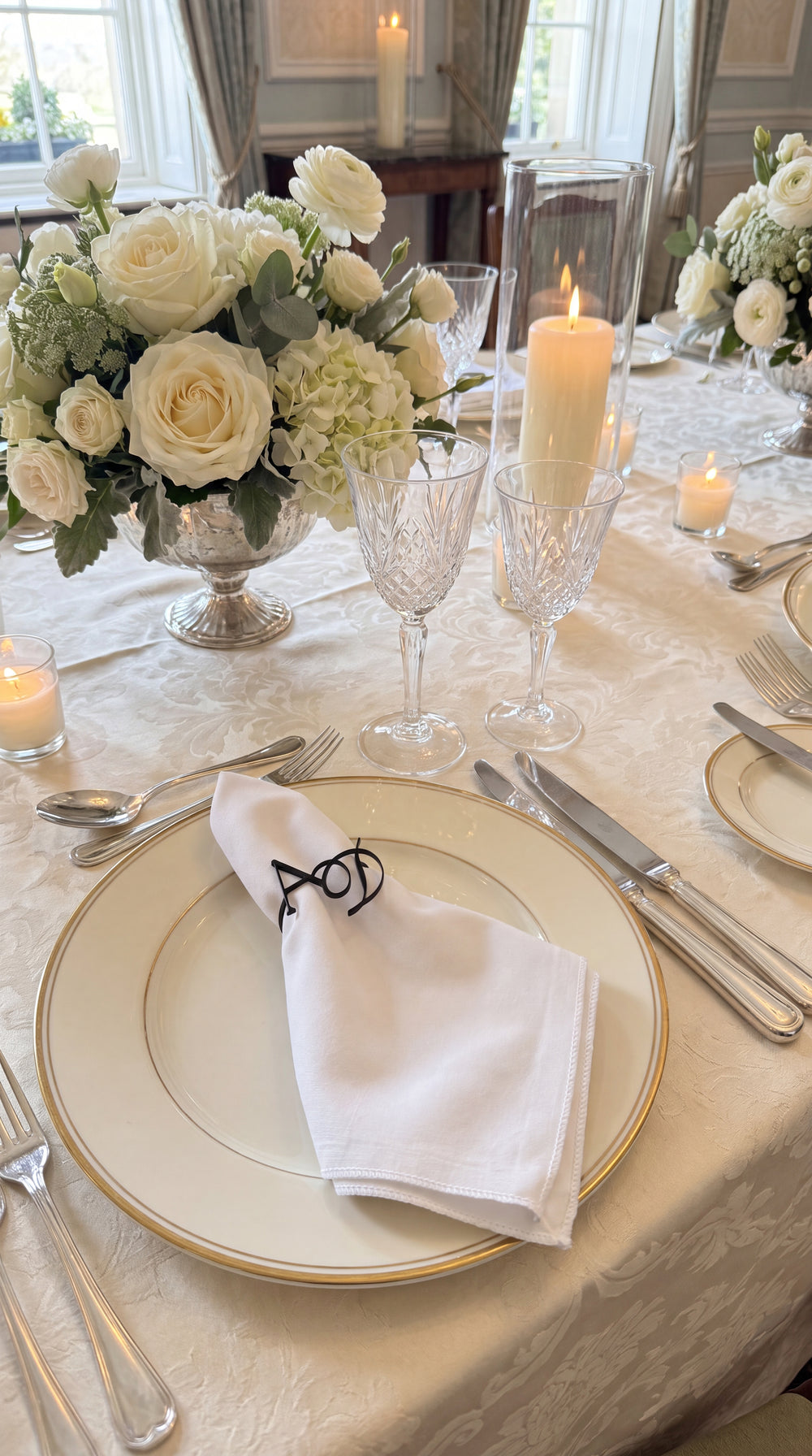 Gold entwined monogram napkin ring on a rolled napkin at a luxury wedding place setting