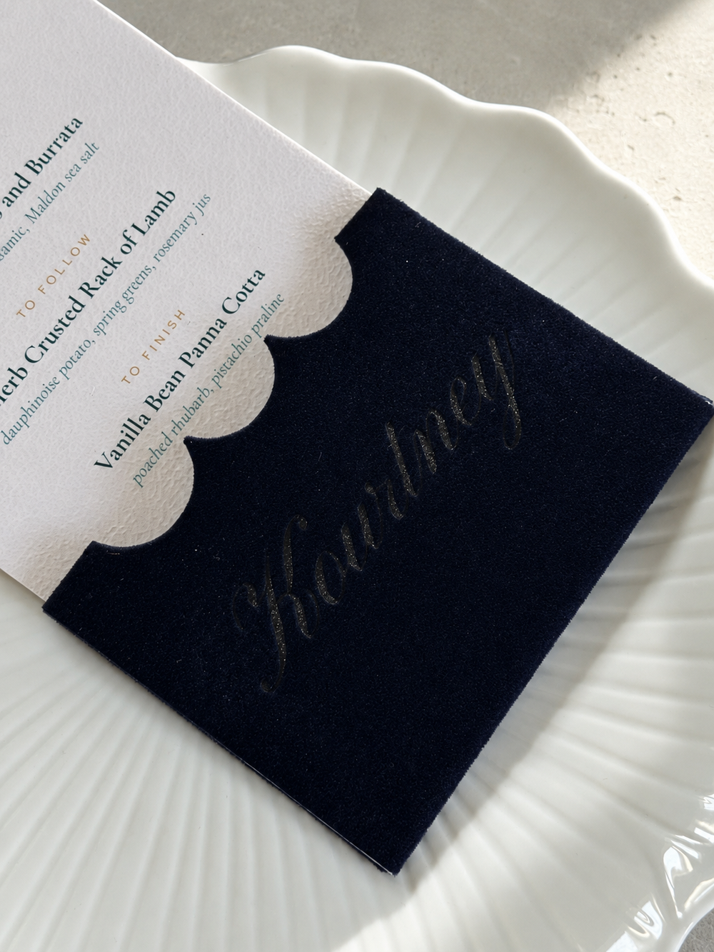 Close view of the name Kourtney engraved into navy velvet in the pearl finish