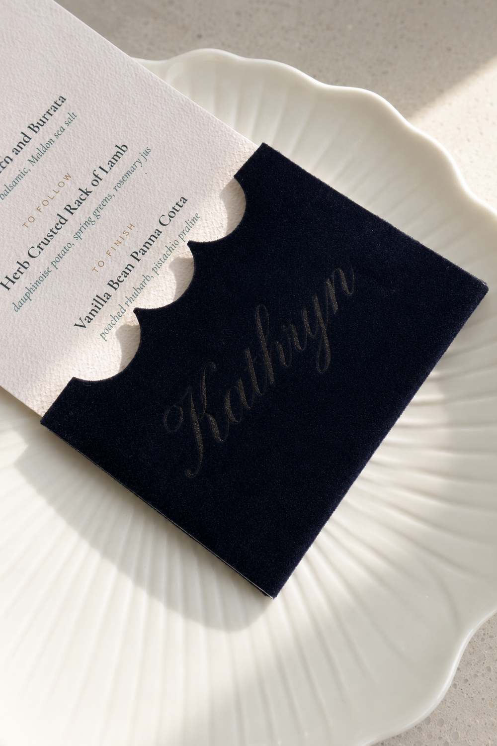 Close view of the name Kathryn engraved into velvet with the printed menu behind
