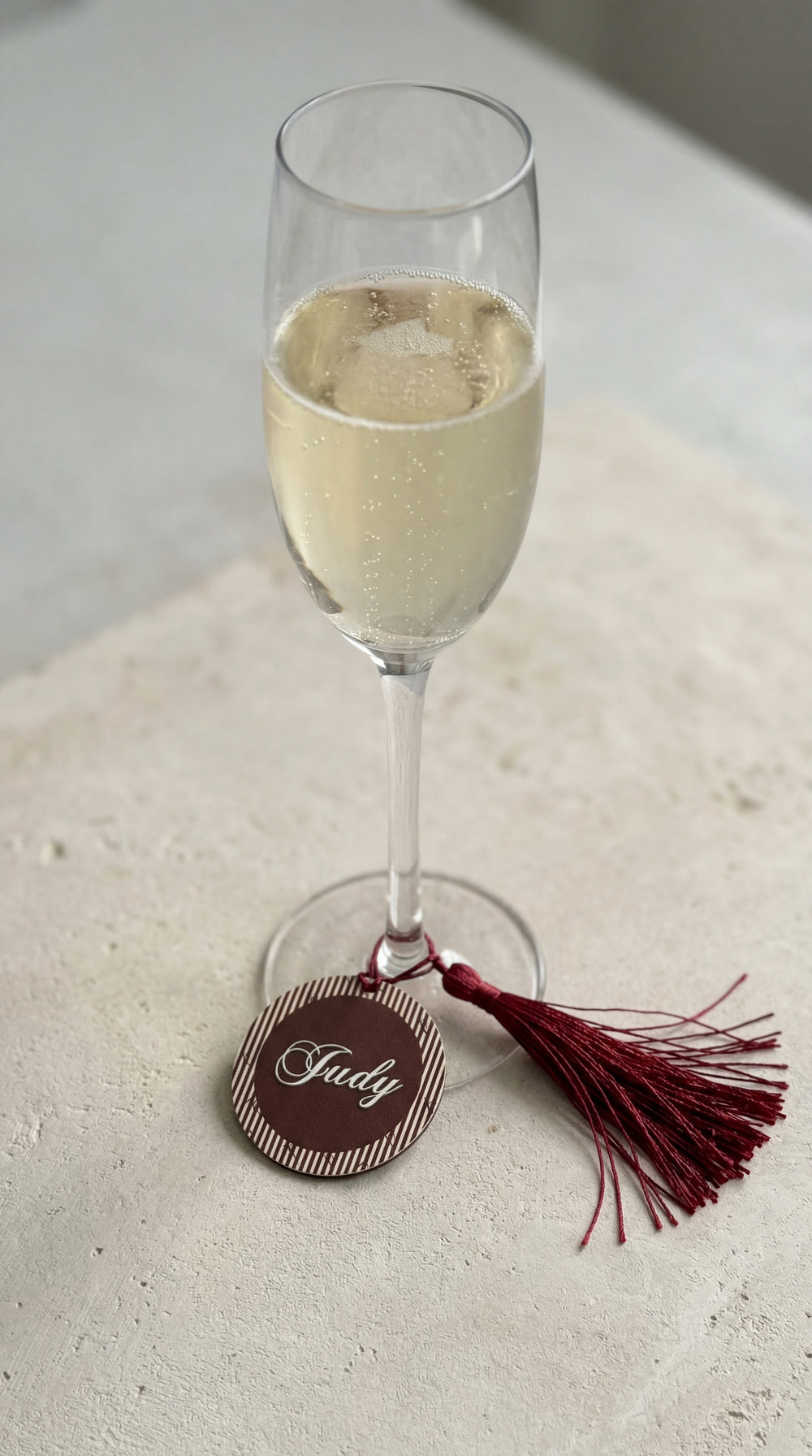 personalised wine glass charm place card with guest name in gold on champagne flute at wedding table