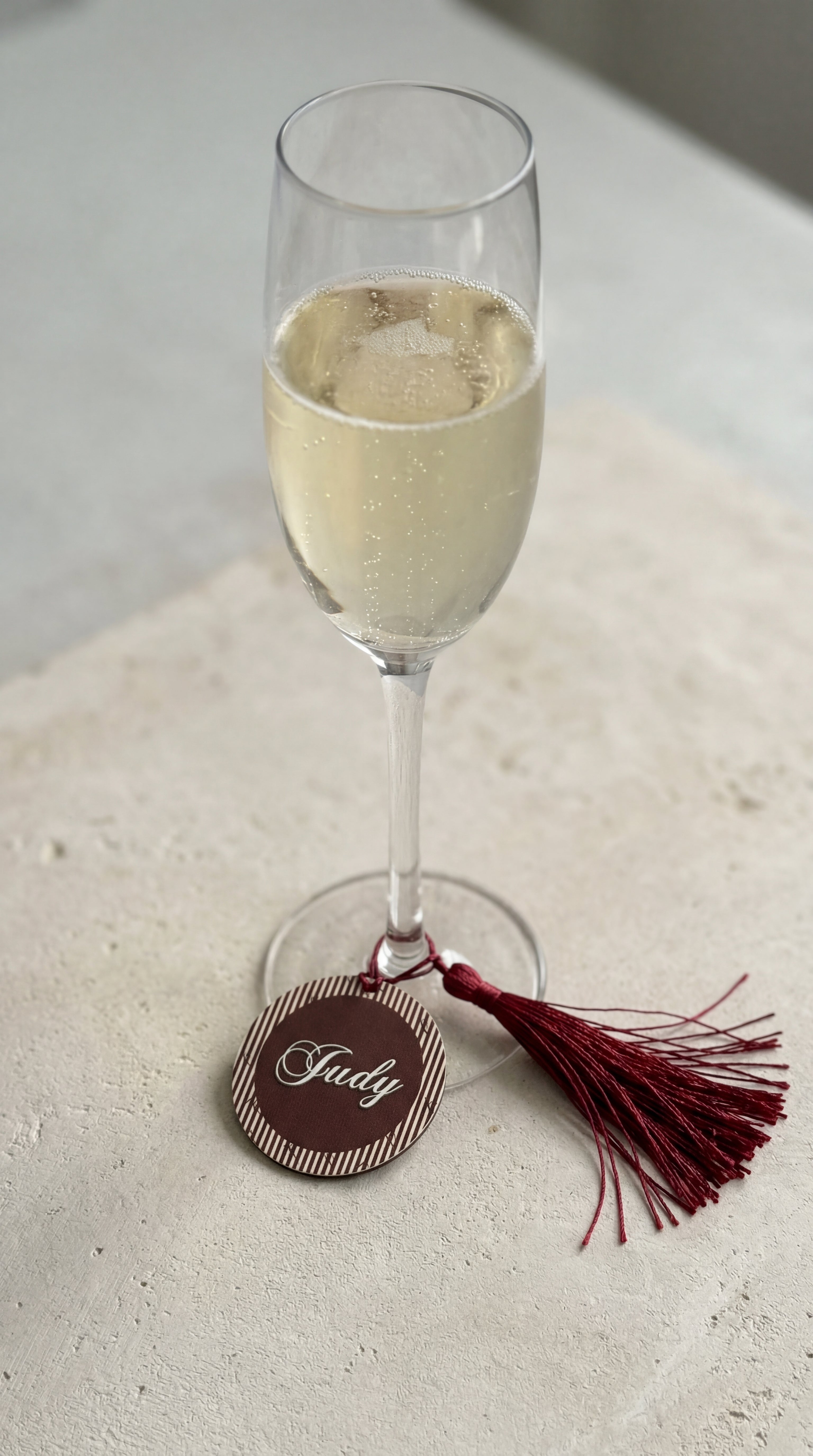 personalised wine glass charm place card with guest name in gold on champagne flute at wedding table