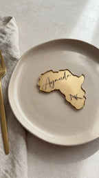 Africa continent shaped clear resin place card with gold leaf and personalised guest name on charger plate