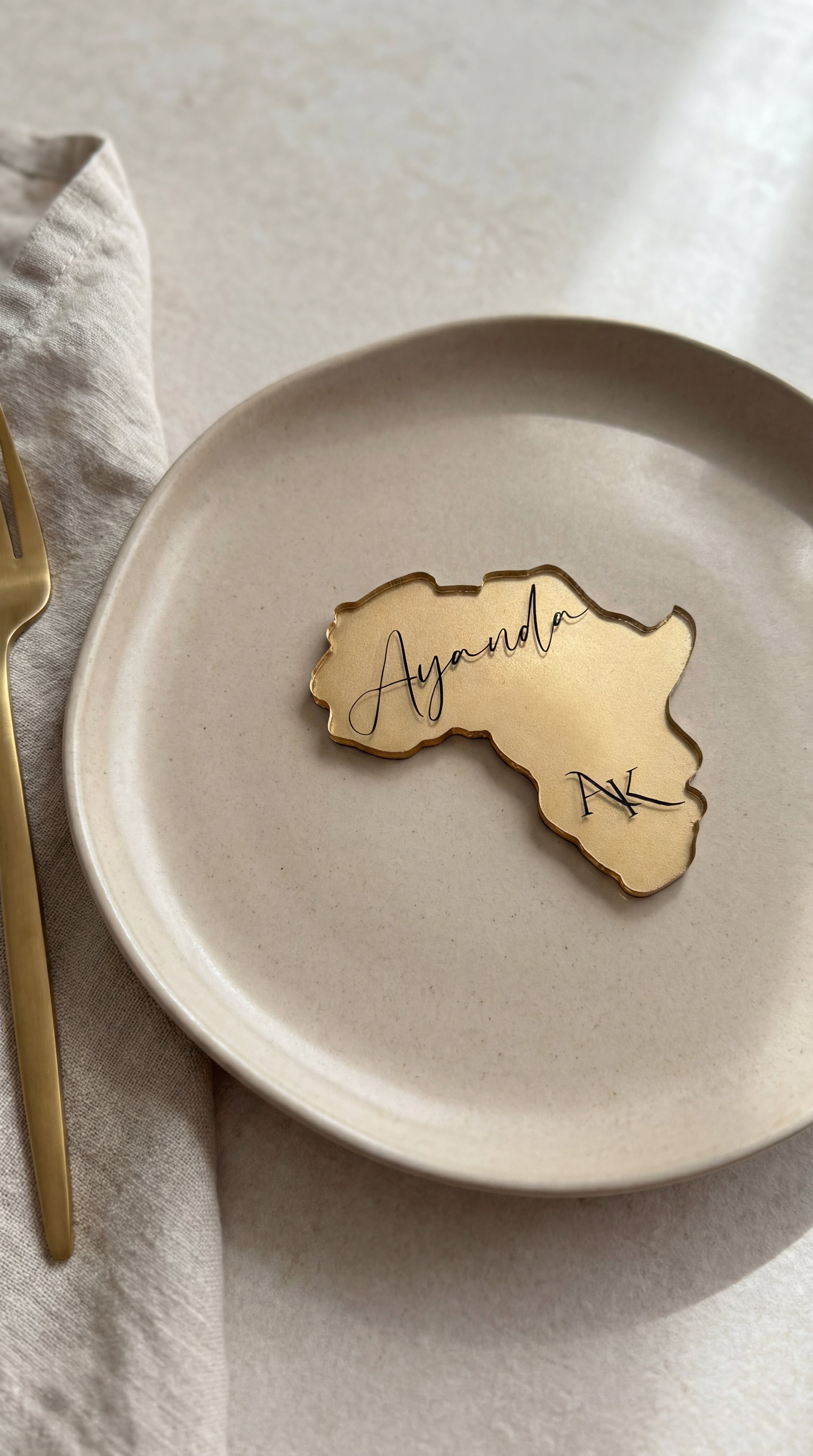 Africa continent shaped clear resin place card with gold leaf and personalised guest name on charger plate